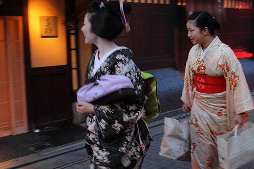 A young Shikomi assists a Geiko to carry her belongings.